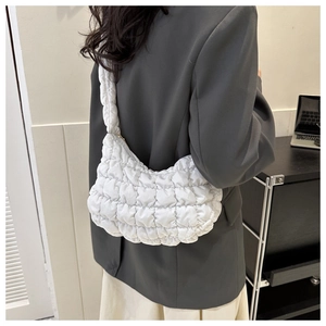 Detail of white quilted cloud bag featuring padded checkered texture on a shoulder strap