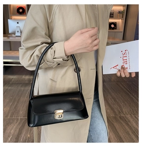 Détail du sac baguette en cuir noir brillant avec fermoir en métal doré chic