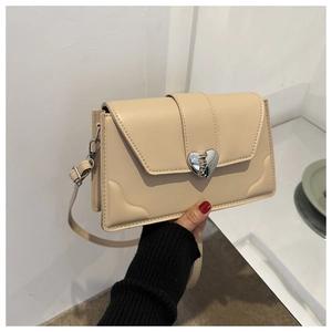 Detail of beige textured shoulder bag featuring silver broken-heart twist lock and fine embossing
