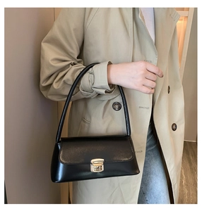 Détail du sac sous le bras en similicuir noir avec boucle dorée sur un trench-coat