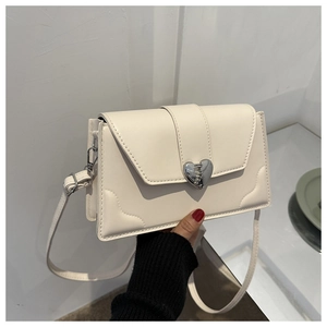 Detailed view of cream crossbody bag featuring a unique heart-shaped silver metal buckle