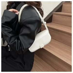 White minimalist shoulder bag with flap design and square buckle on black leather jacket