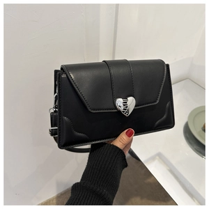 Detailed close-up of the silver heart-shaped metal clasp on a black leather crossbody bag