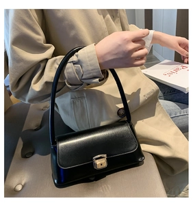 Vue rapprochée de la surface en cuir noir et du fermoir en métal doré de ce sac élégant