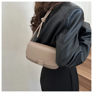 Lifestyle shot showing a beige baguette shoulder bag with a magnetic flap and knot strap