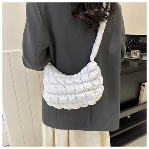 Close-up of white quilted dumpling bag showing plush texture and comfortable shoulder strap