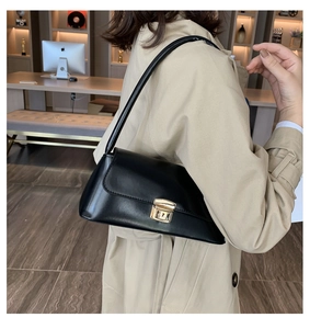 Vue latérale du modèle portant un sac baguette en cuir noir minimaliste avec boucle dorée