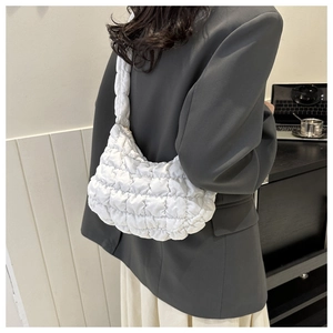 Detailed view of white quilted cloud bag texture and handle on a model's shoulder