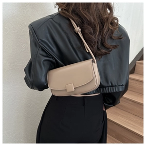 Detail of a beige faux leather crossbody bag with square buckle and knotted strap