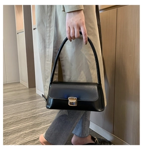 Gros plan du sac sous le bras noir avec boucle rectangulaire dorée et bandoulière simple