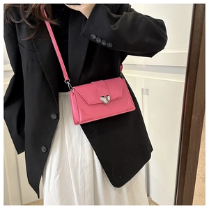 Macro shot of bright pink crossbody bag featuring a silver heart-shaped magnetic buckle