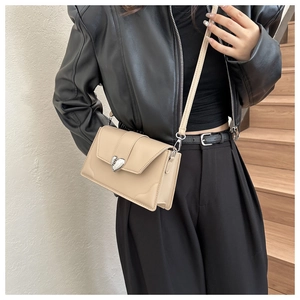 Detail of beige faux leather crossbody bag with silver heart buckle on a model