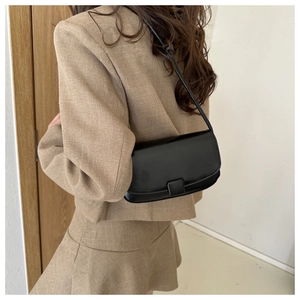Chic black leather underarm bag styled with a neutral suit for a modern minimalist look