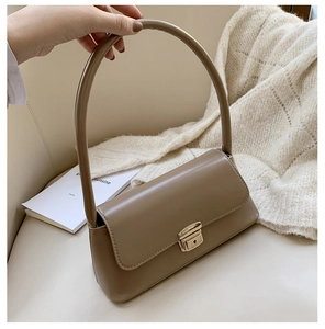 Gros plan d'un sac baguette marron vintage en simili cuir avec fermoir doré sur chaise