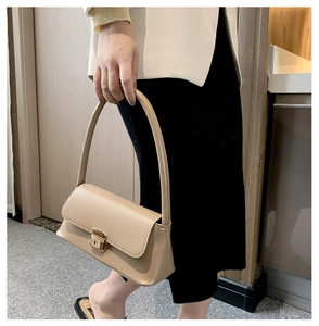 Détail du sac baguette en cuir beige avec un fermoir métallique carré doré et anse longue