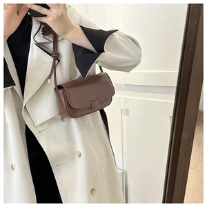 Detail of dark brown leather crossbody bag featuring a unique knotted shoulder strap