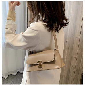 Détail d'un sac sous le bras en cuir beige avec boucle carrée en métal doré et bandoulière