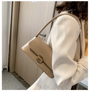 Détail d'un sac baguette kaki avec boucle dorée porté par un mannequin femme