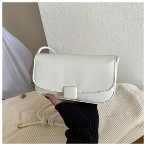 Detail of a creamy white retro square bag with a flap closure and knot-designed strap