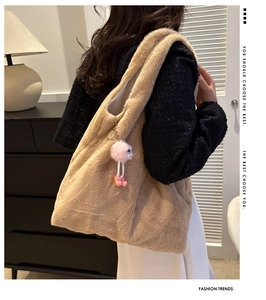 Detailansicht einer großen khakifarbenen Plüschtasche mit rosa flauschigem Anhänger