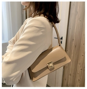 Détail du sac baguette en similicuir beige avec fermoir en métal doré à l'épaule