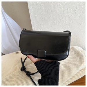 Detail of black PU leather mini square bag with knotted round strap and flap closure