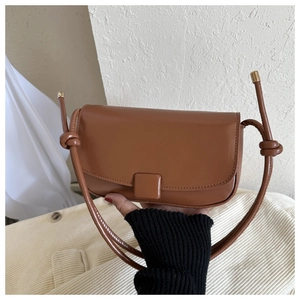 Detail of a brown leather crossbody bag with rectangle flap and knot rope strap
