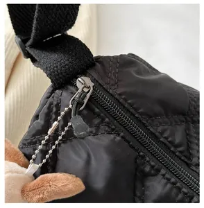 Detailed macro view of smooth silver zipper and chain on black quilted nylon handbag