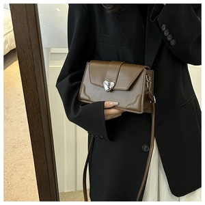 Detail of a brown leather shoulder bag featuring a silver heart-shaped vintage metal buckle