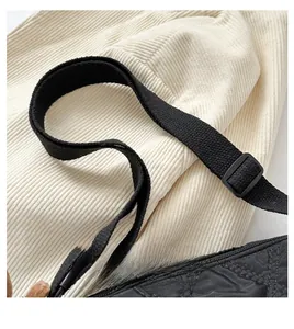 Close-up of adjustable canvas strap and quilted nylon fabric on a black shoulder bag