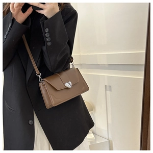 Brown leather crossbody bag featuring a vintage heart-shaped silver metal lock detail