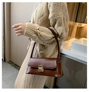 Vue latérale d'une femme portant un sac baguette en cuir marron avec boucle dorée