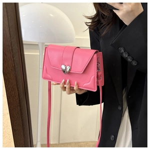 Close-up of pink crossbody bag with silver heart buckle shown in a mirror selfie