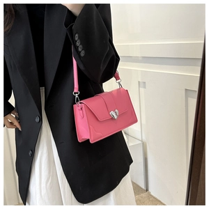 Close-up of pink crossbody bag with silver heart lock shown on black blazer and white skirt