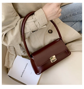 Détail du sac à main rétro en cuir marron foncé avec boucle dorée et poignée ronde