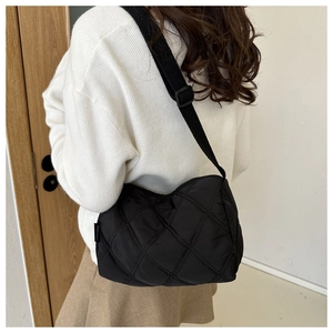 Rear view of a black quilted nylon crossbody bag with adjustable wide strap on a model