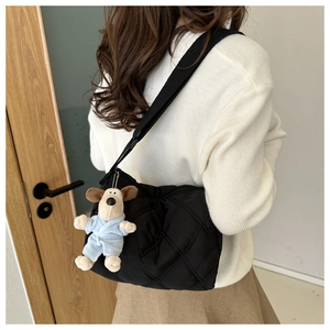 Detail of black quilted nylon crossbody bag with cute dog plush charm on wide strap