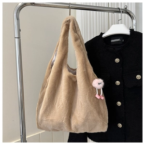 Détail d'un sac fourre-tout en peluche beige avec un charme d'œil rose suspendu au support