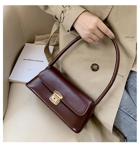 Détail du sac baguette en cuir bordeaux avec fermoir doré vintage sur une chaise