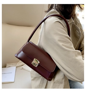 Gros plan d'un sac baguette en similicuir marron foncé avec boucle en métal doré