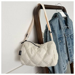Detail of cream quilted nylon crossbody bag featuring soft rhombic stitching and side label