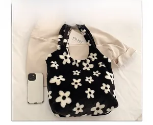 Top-down view of black fuzzy plush tote bag with white flower patterns and soft texture
