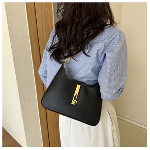 Detail of a chic black leather underarm bag with gold metal chain and ring clasp