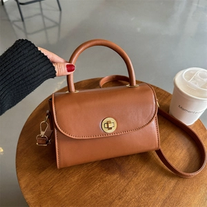 Retro brown leather crossbody bag with golden hardware on a rustic wooden table