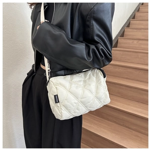 Dettaglio della borsa a tracolla trapuntata beige con cuciture a rombi e tracolla in tessuto