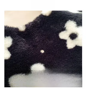 Macro detail of soft black plush fabric featuring white five-petal floral patterns