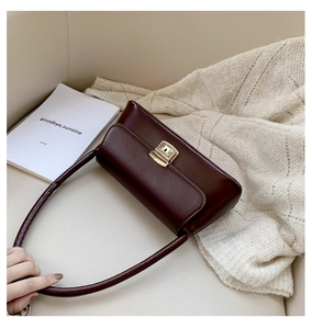 Détail du sac vintage bordeaux avec fermoir doré sur fond beige et maille blanche