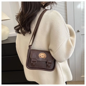 Détail du sac à bandoulière en cuir marron avec un joli écusson brodé de chien de dessin animé