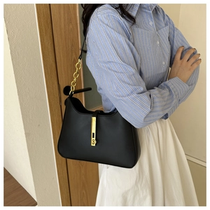 Detail of a vintage black crescent underarm bag with a bold gold chain and metal buckle