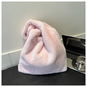 Nahaufnahme der weichen rosa Kunstpelz-Tasche auf einem modernen Holzschreibtisch